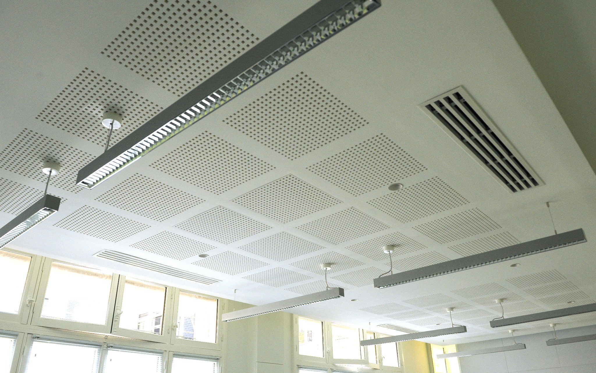 Faux plafond perforé avec luminaires suspendus et grilles de ventilation intégrées